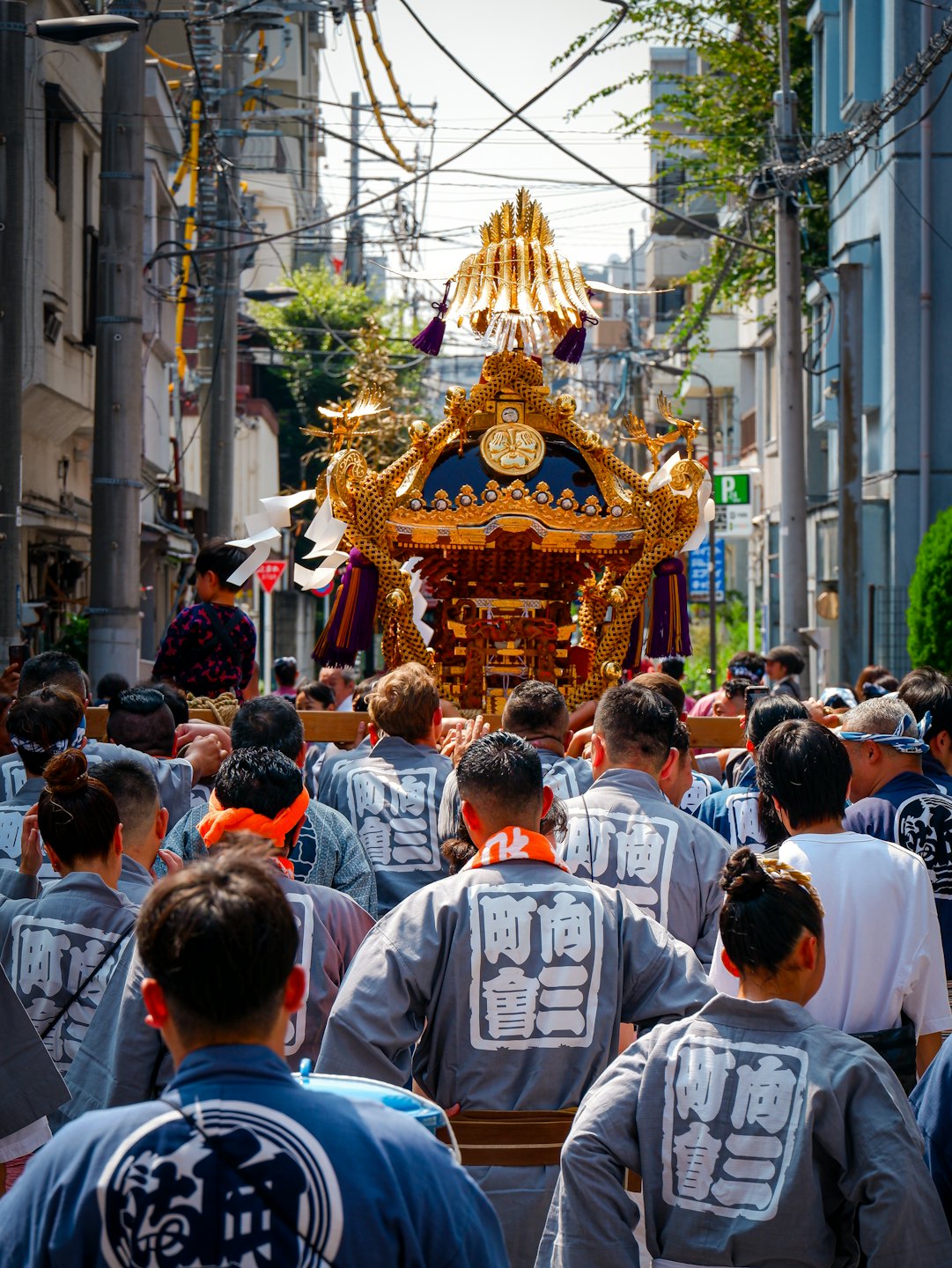 伝統的な衣装を着た人々が、装飾された金色の神輿を担いでいる。