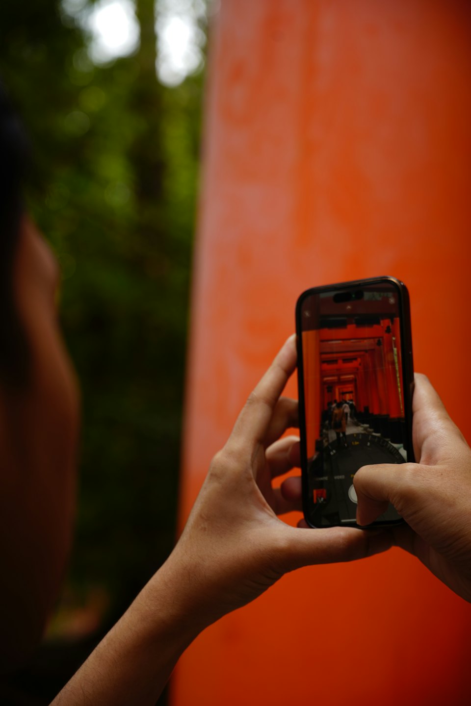 スマートフォンを持つ手、赤い鳥居の道が表示されている。