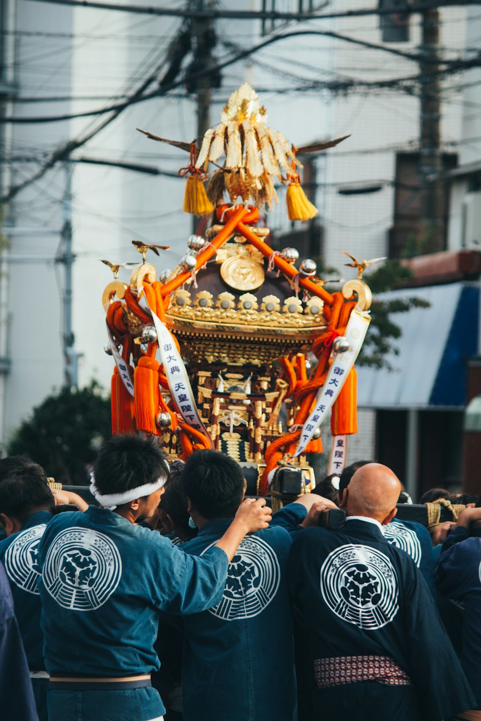 法被を着た男性たちが、祭りで黄金のみこしを担いでいる。