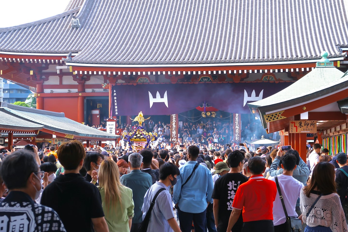 日本の寺院で行われる伝統的な祭りの行列を観衆が見守る様子。